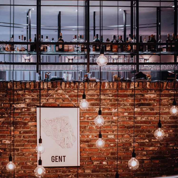 de centrale middeleeuwse muur in het restaurant met zicht op bar, verlichting en een poster van gent