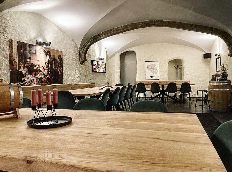 Brasserie Uilenspiegel Gent - de crypte met tafels en stoelen voor ontvangst van een groep of groepen in ons restaurant met zicht op de poster van stad gent en het schilderij van rembrandt
